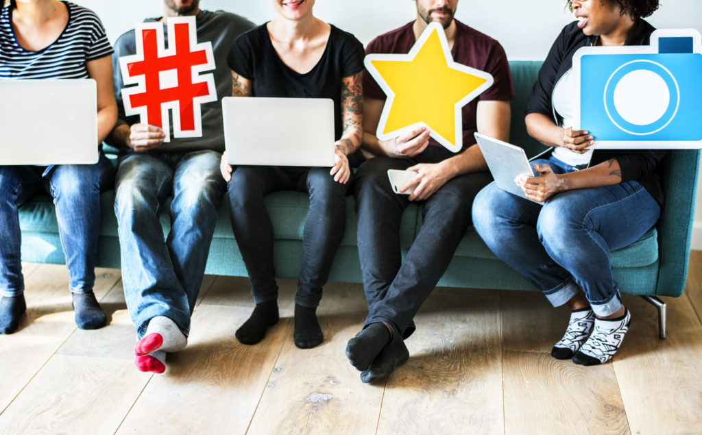 A group of people sitting on a couch with laptops.