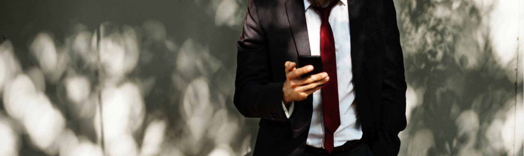 A man in a suit is holding a cell phone.