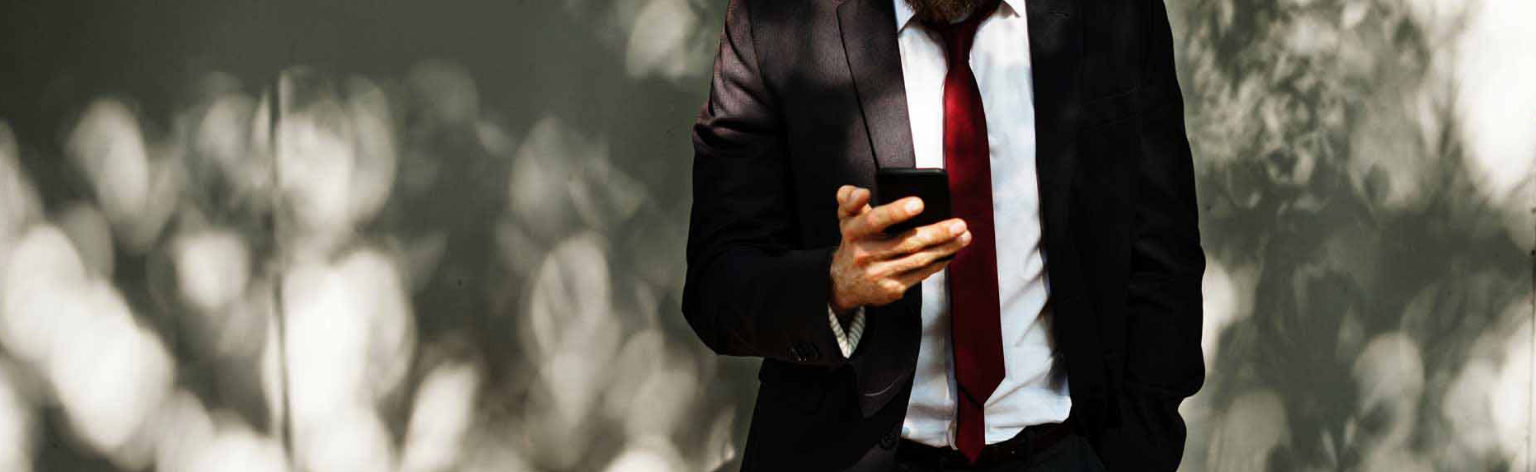 A man in a suit is holding a cell phone.