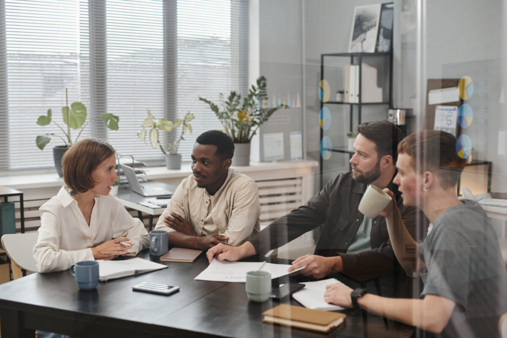 Group of business colleagues sitting at the table and discussing during a meeting in the boardroom behind the glass wall
