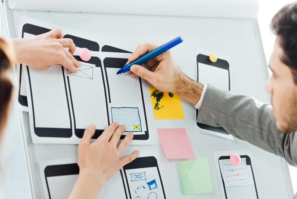 Selective focus of developers with marker working with wireframe sketches for optimizing the website for mobile