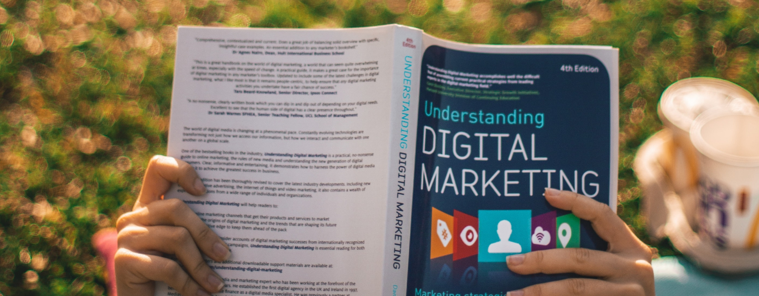 A person studying internet marketing through a book.