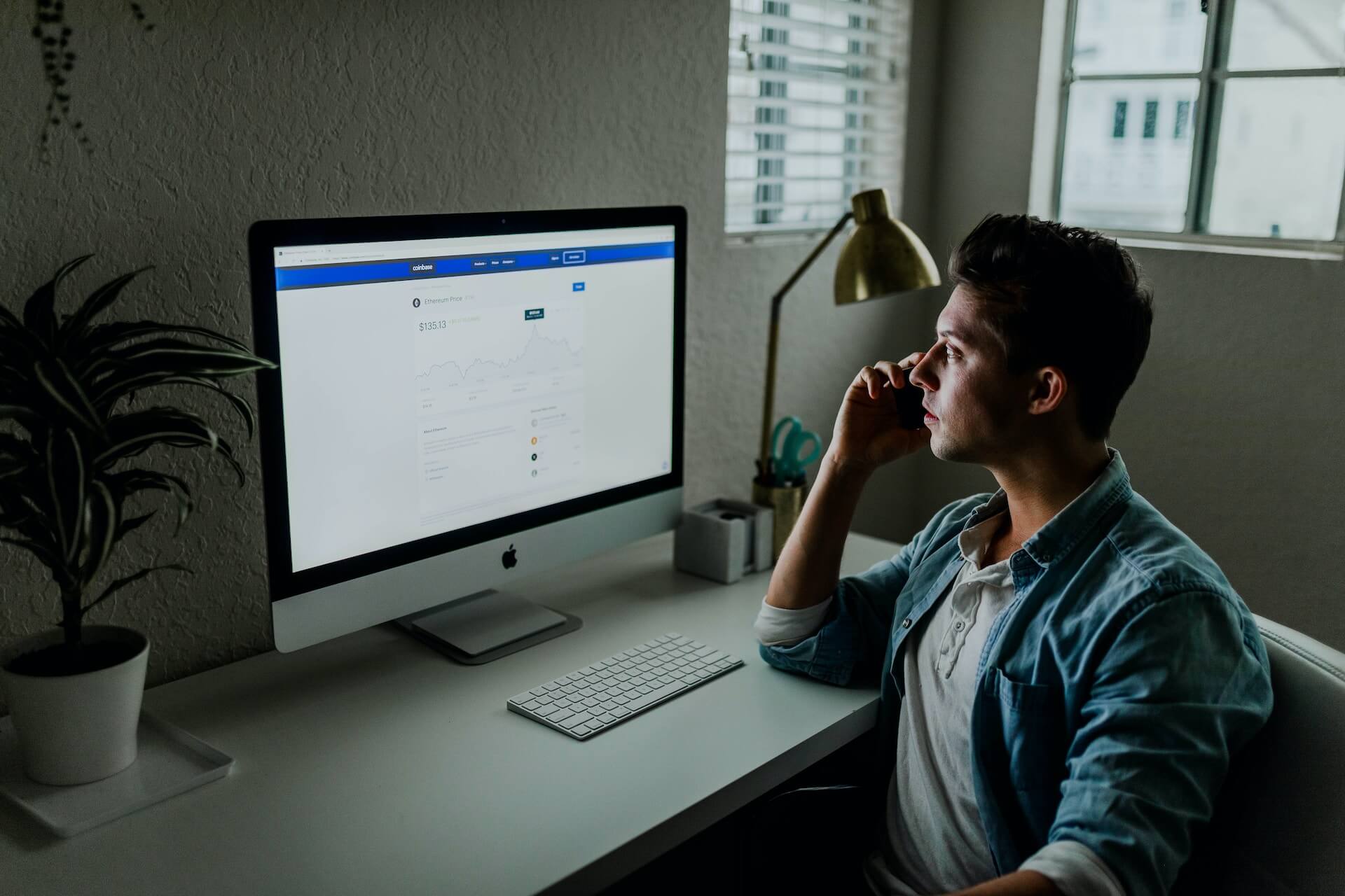 A man sitting in front of a computer screen looking at facebook.