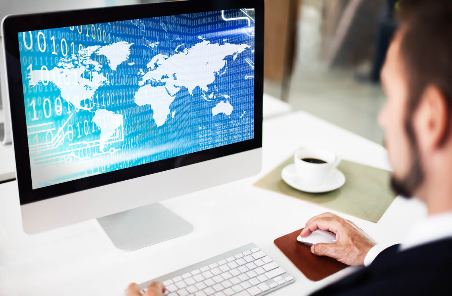 A man is working on a computer with a world map on it.