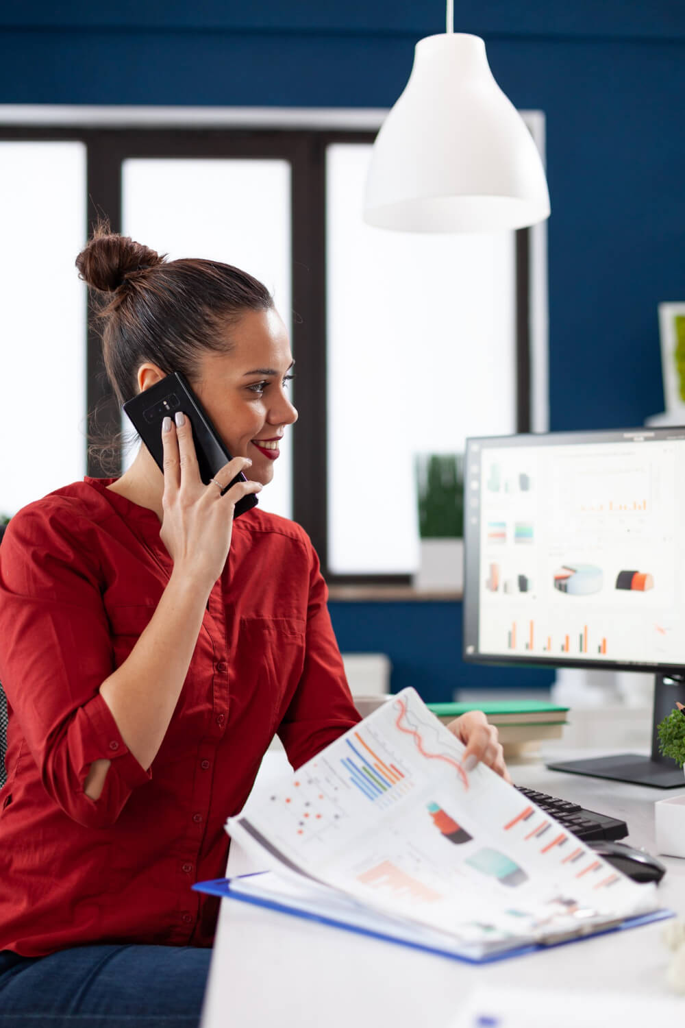 A woman is talking on the phone while sitting at a desk.