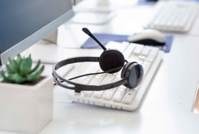 A headset sits on a desk next to a keyboard.