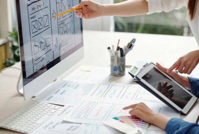 Two people working on a computer at a desk.