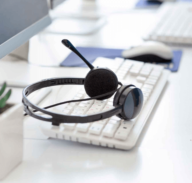 A headset sits on a desk next to a keyboard.