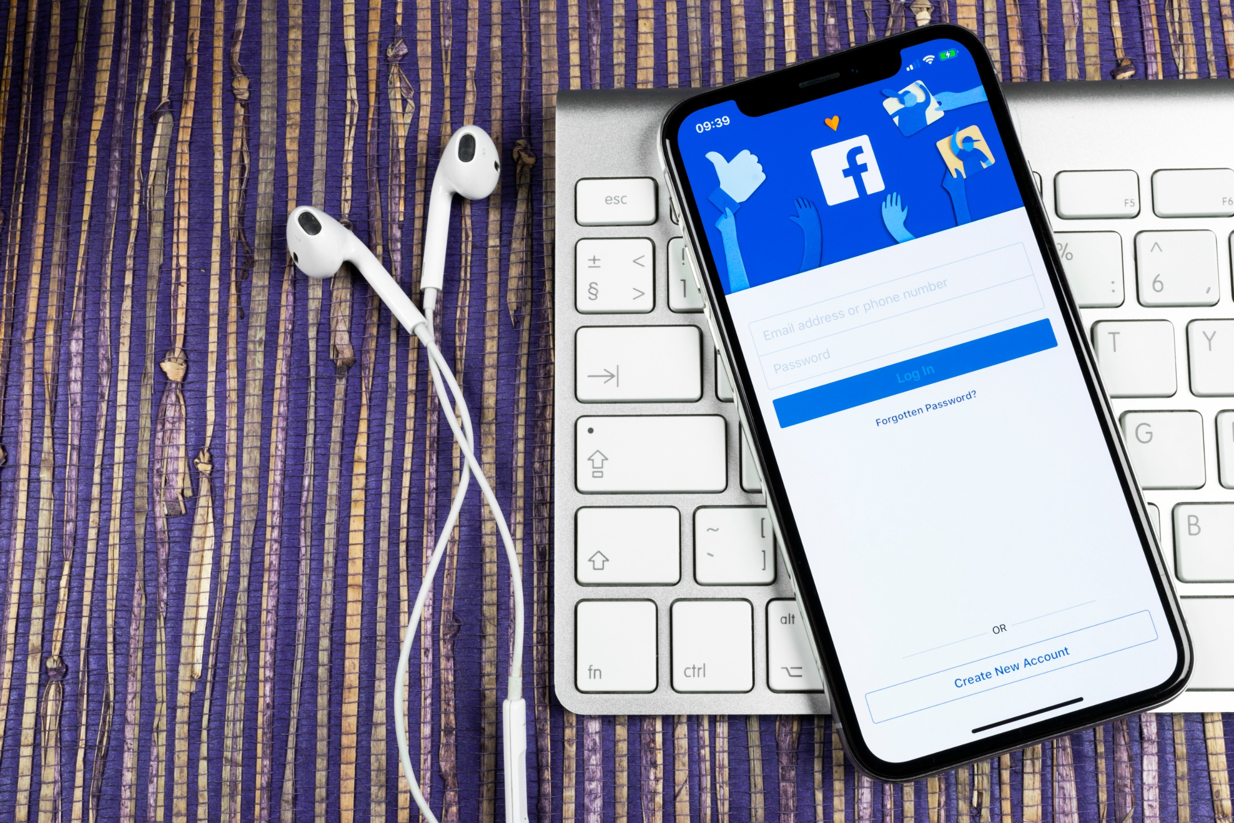 A phone with the facebook logo on it next to a keyboard.